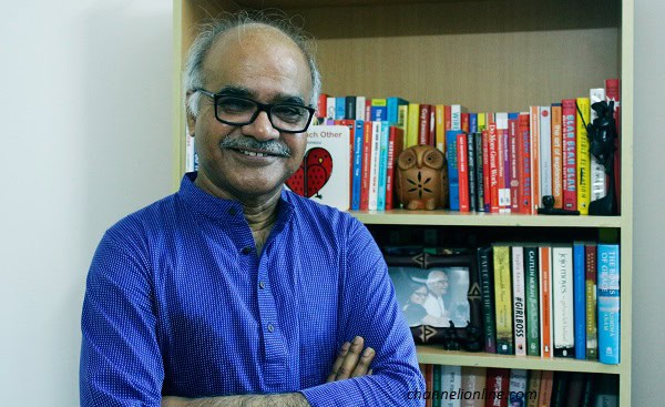 চ্যানেল আই অনলাইন এর ব্যক্তিগত ছবি, একজন ব্যক্তি বইয়ের শেলফের সামনে হাসছেন. Channel i News - চ্যানেল আই নিউজ