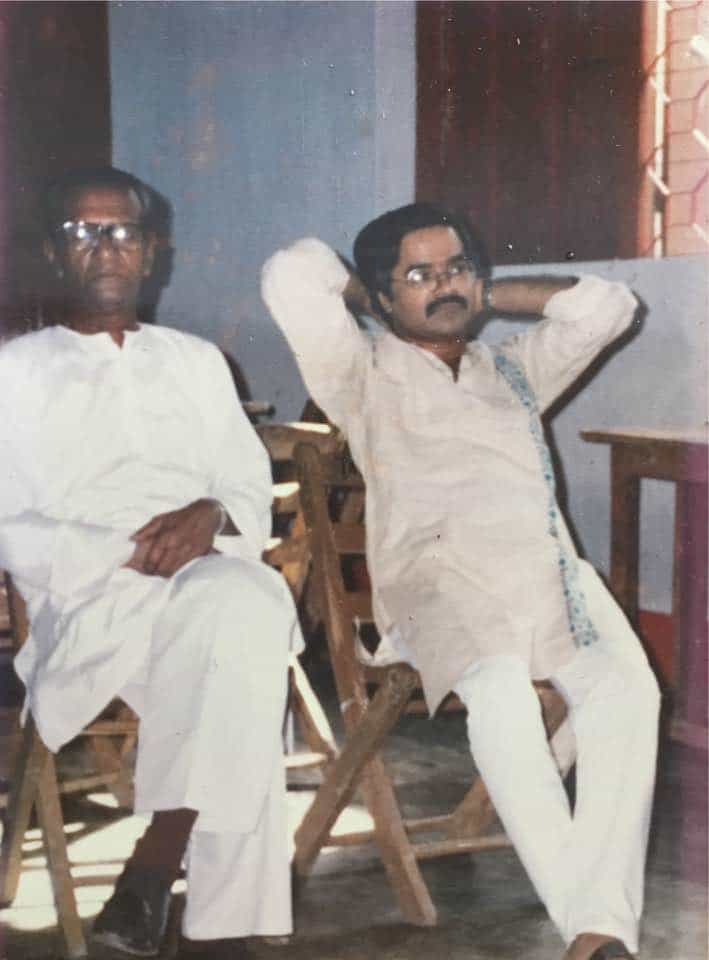 Two Bangladeshi men sitting on wooden chairs indoors. Channel i News - চ্যানেল আই নিউজ