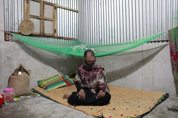 Bangladeshi garments worker Rina Begum, 25, sits inside of her home and poses for photo.