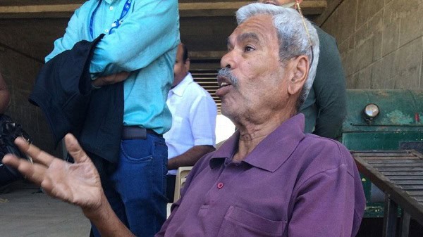 বয়স্ক ব্যক্তি কথা বলছেন, পেছনে অন্যরা দাঁড়িয়ে আছেন।. Channel i News - চ্যানেল আই নিউজ
