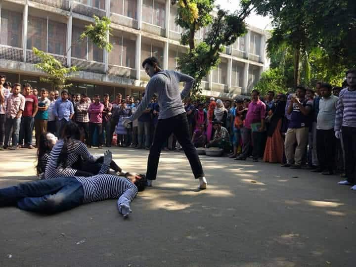জনতা মূকনাট্য দেখছে, এক ব্যক্তি অন্যকে মারছে, নাটকের দৃশ্য. Channel i News - চ্যানেল আই নিউজ