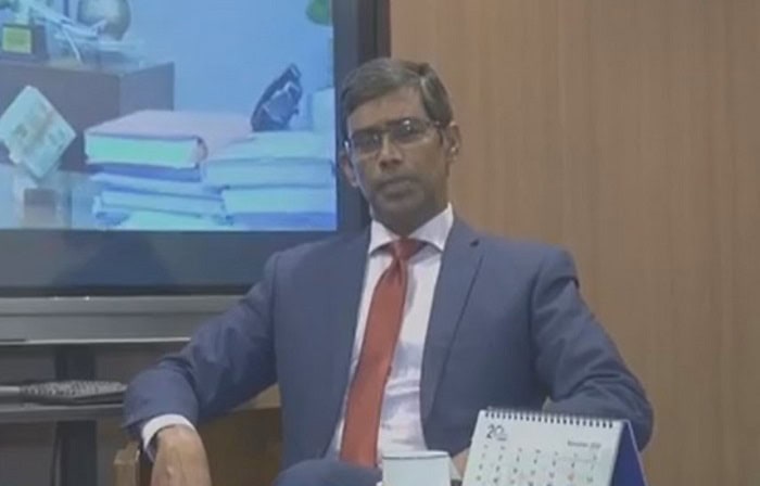 অফিসে বসে একজন পুরুষ কর্মকর্তা, পেছনে ডেস্ক ও ক্যালেন্ডার দেখা যাচ্ছে. Channel i News - চ্যানেল আই নিউজ