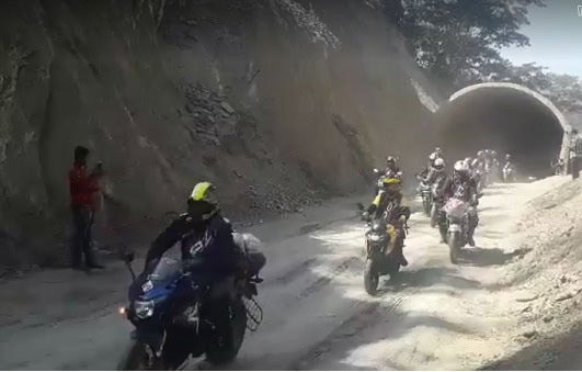 Motorcycles passing through a mountain tunnel on a dusty road. Channel i News - চ্যানেল আই নিউজ