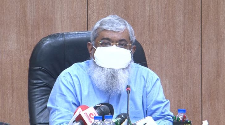 বাংলাদেশের একজন সরকারী কর্মকর্তা মুখে মাস্ক পরে বসে আছেন।. Channel i News - চ্যানেল আই নিউজ