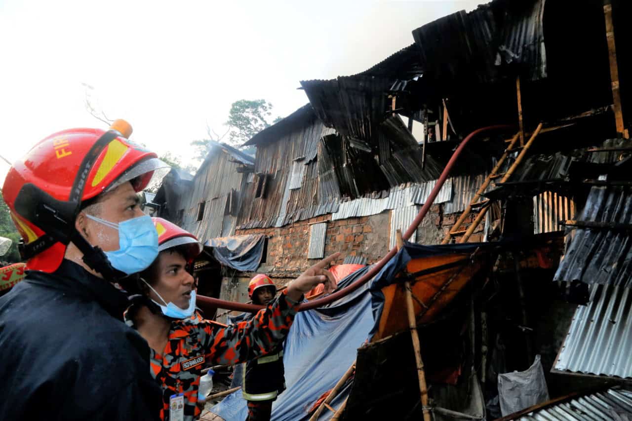 Firefighters inspect the burnt structure after the Mahakhali slum fire. Channel i News - চ্যানেল আই নিউজ