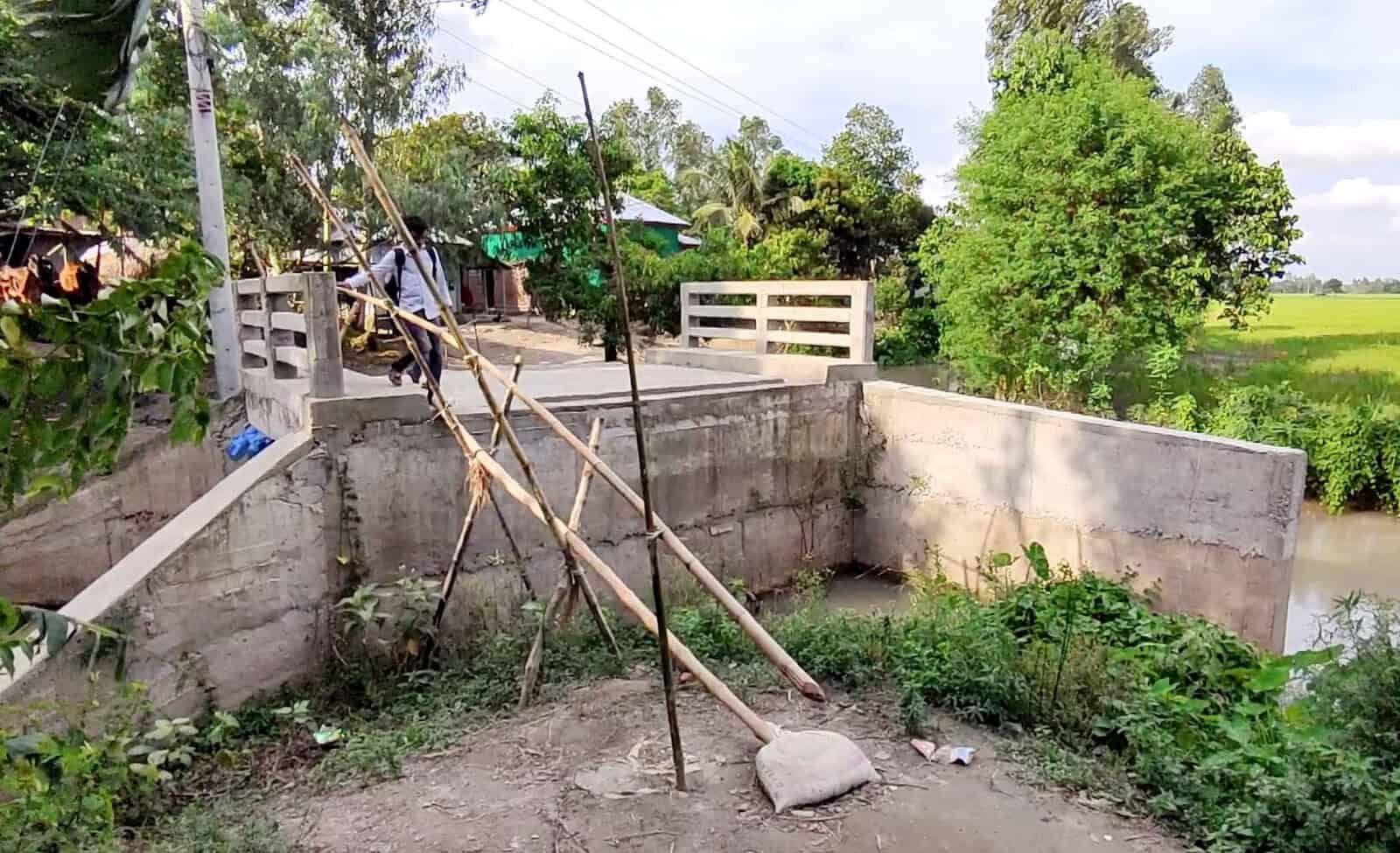 বাঁশের খুঁটির সাহায্যে কালভার্টে উঠার চেষ্টা করছে মানুষ. Channel i News - চ্যানেল আই নিউজ
