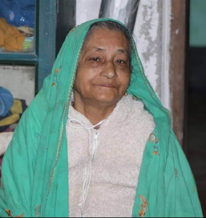 বৃদ্ধা নারী, হালকা হাসি, সবুজ শাড়ি পরা, ঘরে বসে ছবি. Channel i News - চ্যানেল আই নিউজ