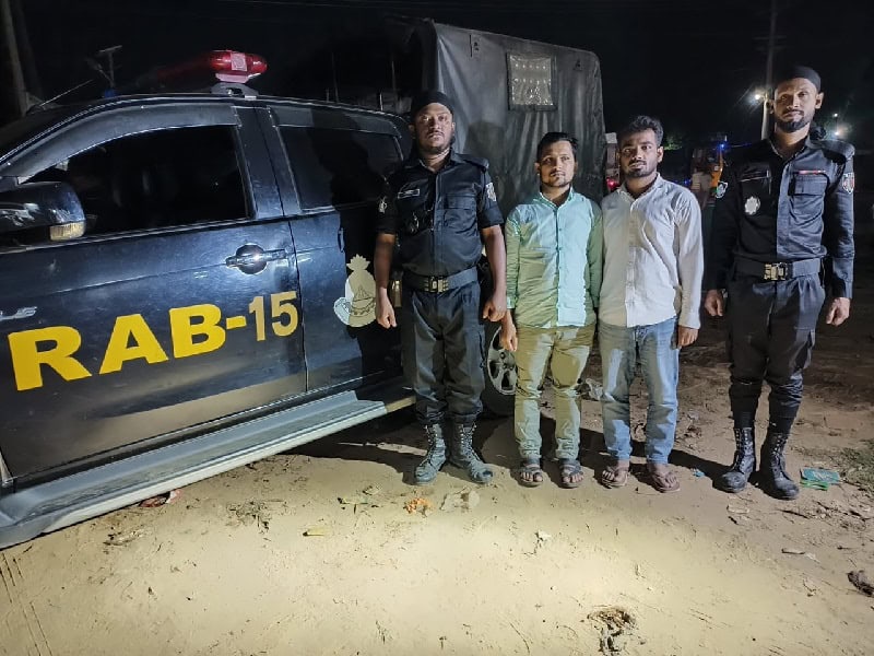 Police officers and two men standing beside a RAB vehicle at night. Channel i News - চ্যানেল আই নিউজ