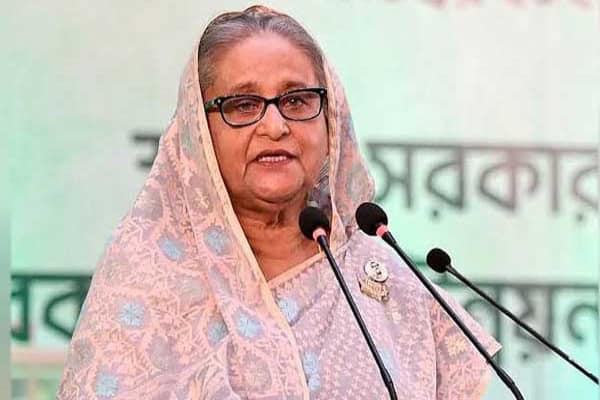 প্রধানমন্ত্রী শেখ হাসিনা ভাষণ দিচ্ছেন, পত্রিকা ও মাইক্রোফোনের সামনে. Channel i News - চ্যানেল আই নিউজ