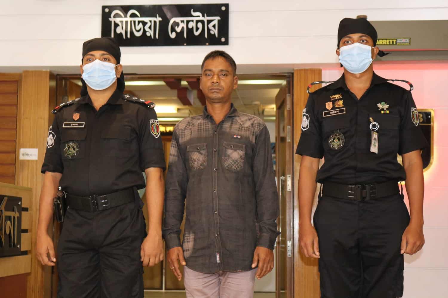 দুটি পুলিশ সদস্যের সঙ্গে একজন ব্যক্তি, সবাই মাস্ক পরা, বাংলাদেশে. Channel i News - চ্যানেল আই নিউজ