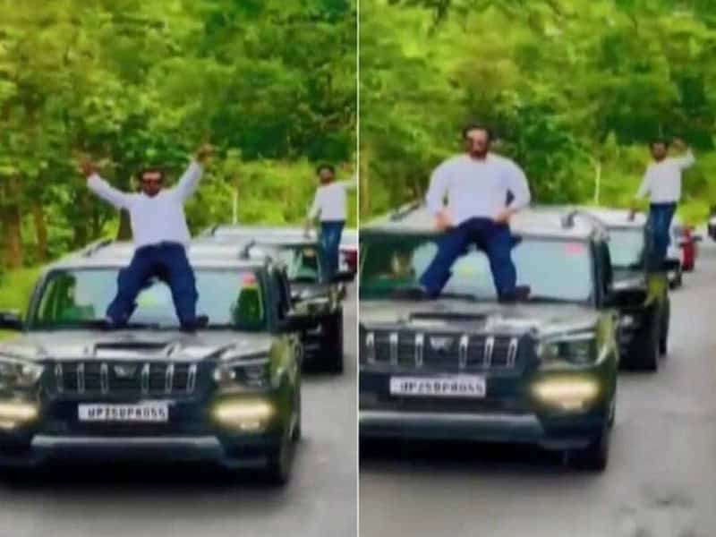 গাড়ির ছাদে বসে থাকা যুবক ও চালক, সবুজ গাছের পেছনে. Channel i News - চ্যানেল আই নিউজ