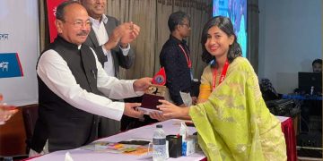 পুরস্কার গ্রহণ করছেন একজন তরুণ নারী ও পুরস্কার প্রদানকারী ব্যক্তি. Channel i News - চ্যানেল আই নিউজ