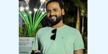 আনন্দিত যুবক মোবাইল ফোনে হাসিমুখে দাঁড়িয়ে. Channel i News - চ্যানেল আই নিউজ