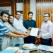 নেতৃস্থানীয় ব্যক্তির হাতে বই প্রদান অনুষ্ঠানে অংশগ্রহণকারী ব্যক্তিরা. Channel i News - চ্যানেল আই নিউজ