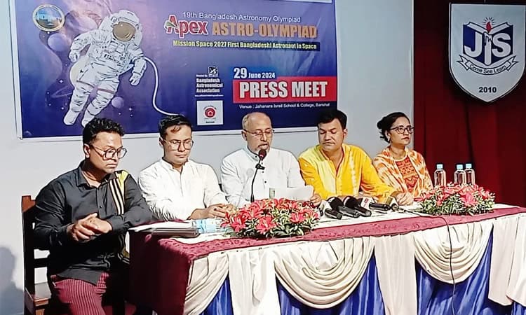 প্রেস কনফারেন্সে অংশগ্রহণকারী ব্যক্তিরা বসে আছেন, পেছনে অ্যাস্ট্রো-অলিম্পিয়াডের ব্যানার।. Channel i News - চ্যানেল আই নিউজ
