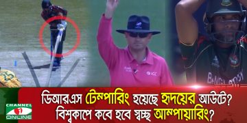 Cricket umpire signaling during a match with a player in the background. Channel i News - চ্যানেল আই নিউজ
