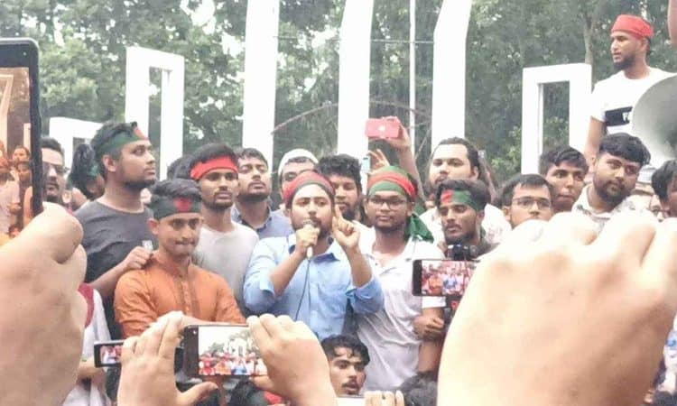 জনতা সমাবেশে বক্তা ভাষণ দিচ্ছেন, অনেক মানুষ উপস্থিত. Channel i News - চ্যানেল আই নিউজ