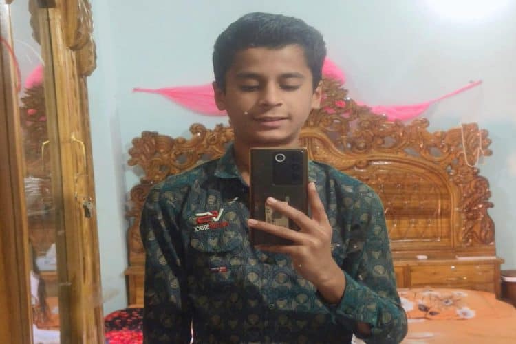 ছাত্রের ছবি, সে মোবাইল দিয়ে ছবি তুলছে, বিছানার পাশে কাঠের আসবাবপত্র. Channel i News - চ্যানেল আই নিউজ