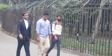 তিন ব্যক্তি জেলেপাড়ার রাস্তায় হাঁটছেন, পেছনে জাল ও তারের বেড়া. Channel i News - চ্যানেল আই নিউজ