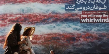 তেহরানে যুক্তরাষ্ট্রবিরোধী একটি বিলবোর্ডের পাশ দিয়ে হেঁটে যাচ্ছেন কিছু মানুষ