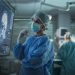 Professional Focused Caucasian Female Surgeon Reviewing Patient's Brain Scans on a Large Monitor, Preparing to Lead Her Team in a Complex Surgery, Analyzing Data Before the Procedure Begins